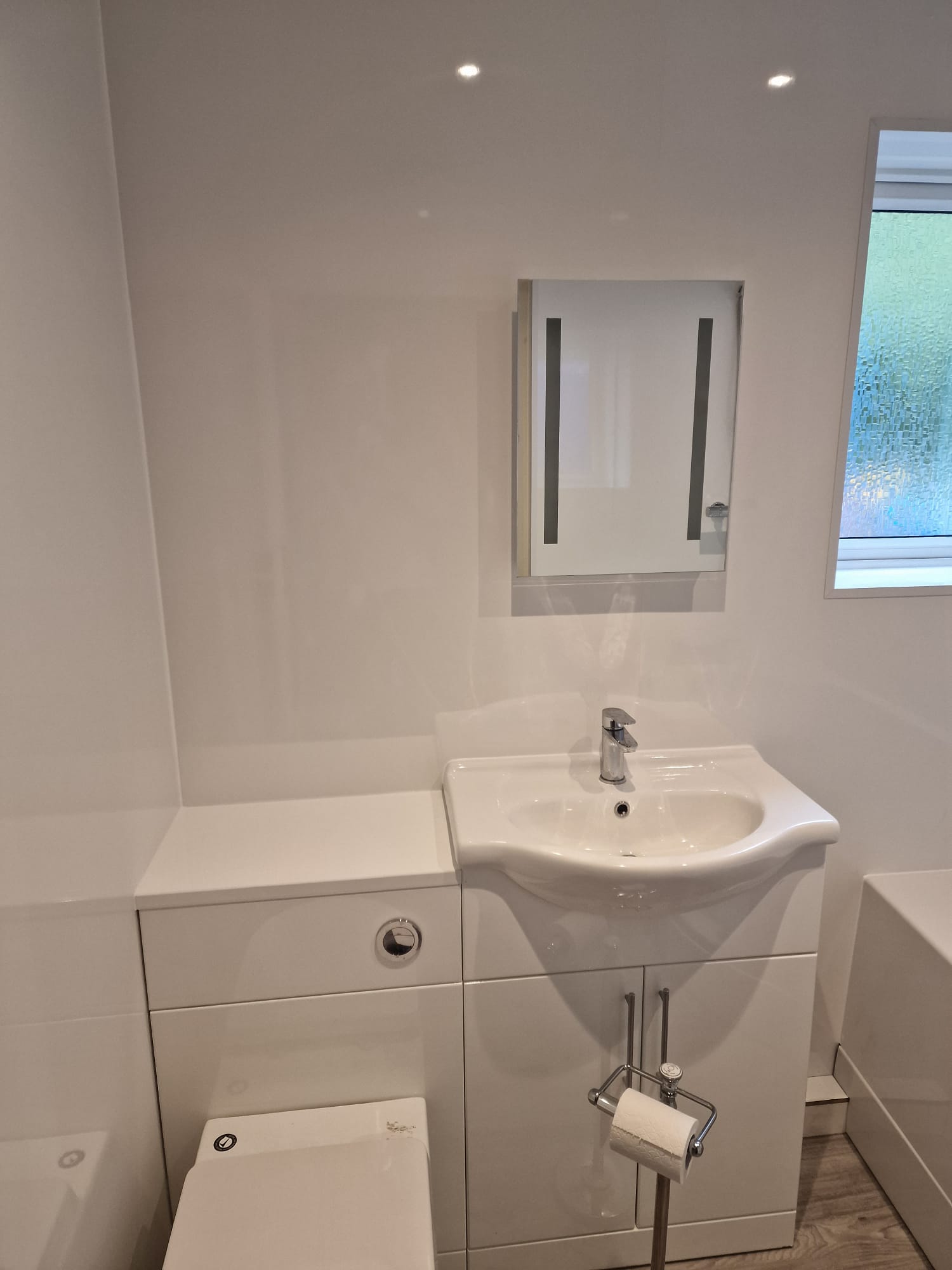 Bright white gloss bathroom vanity unit with concealed-cistern WC and chrome accessories
