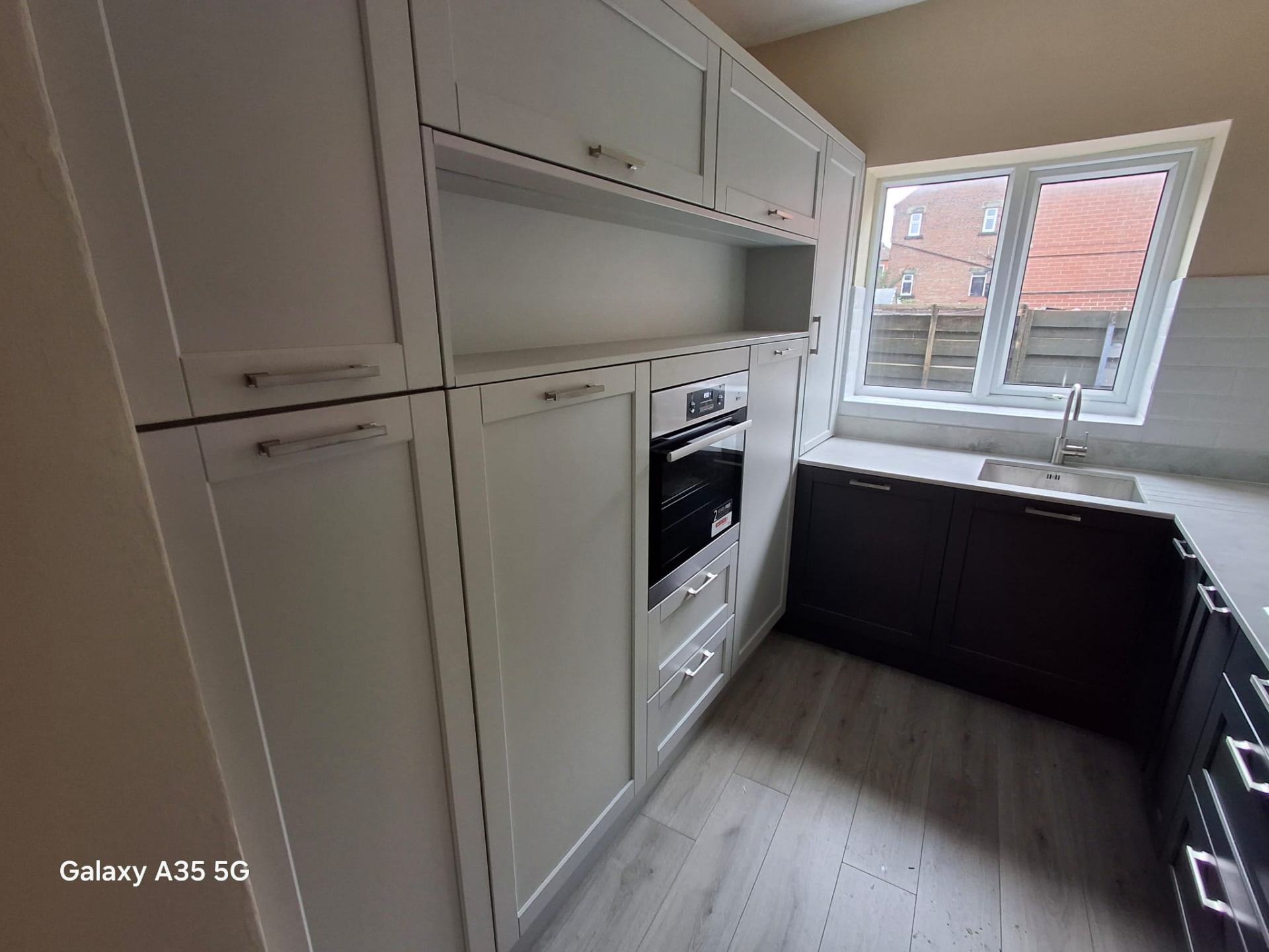Light grey and navy shaker kitchen with integrated single oven and laminate stone-effect worktop