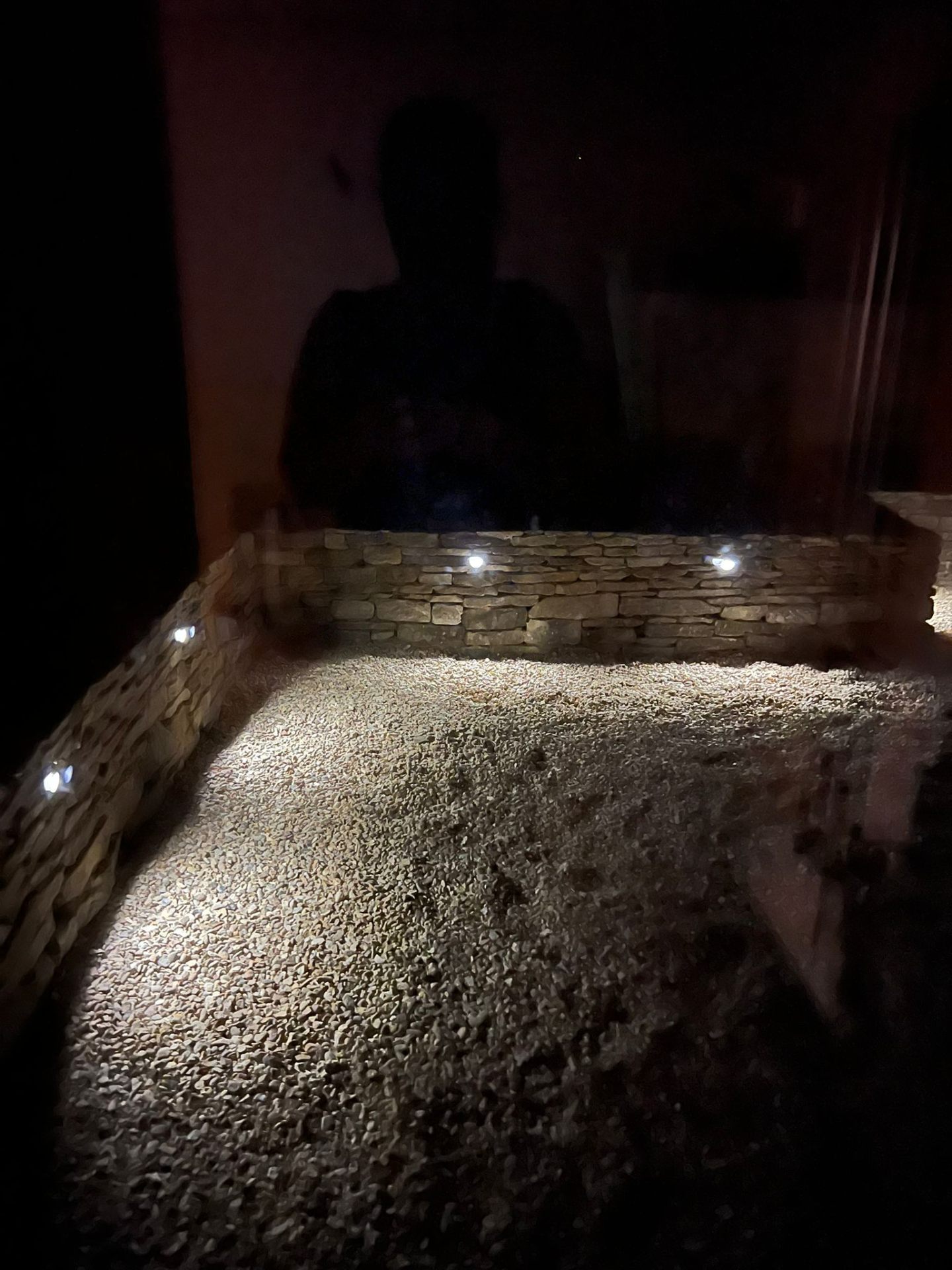 Hand-built dry-stone garden wall with integrated low-voltage LED lighting at dusk