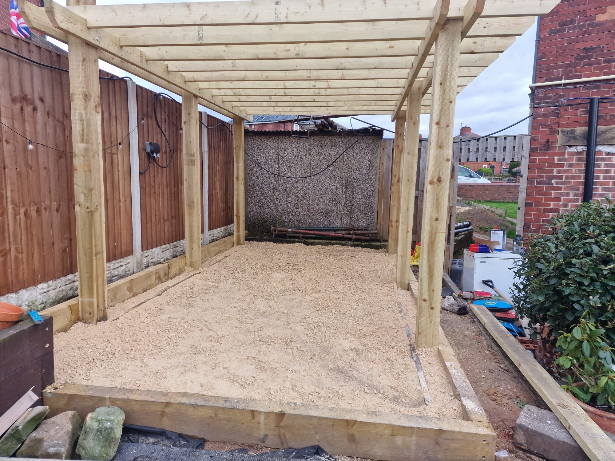 Newly built timber pergola structure with sleeper-edged gravel base in a Yorkshire back garden