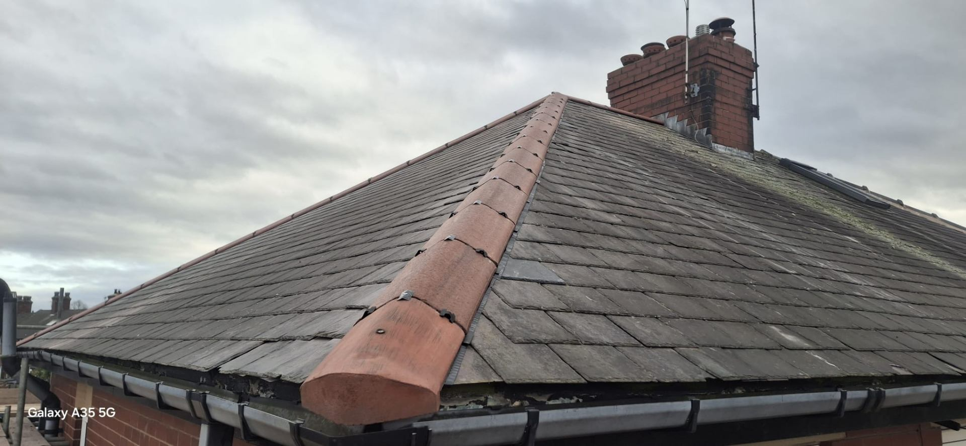 Pitched slate roof with re-bedded clay ridge tiles and traditional brick chimney on a Yorkshire home